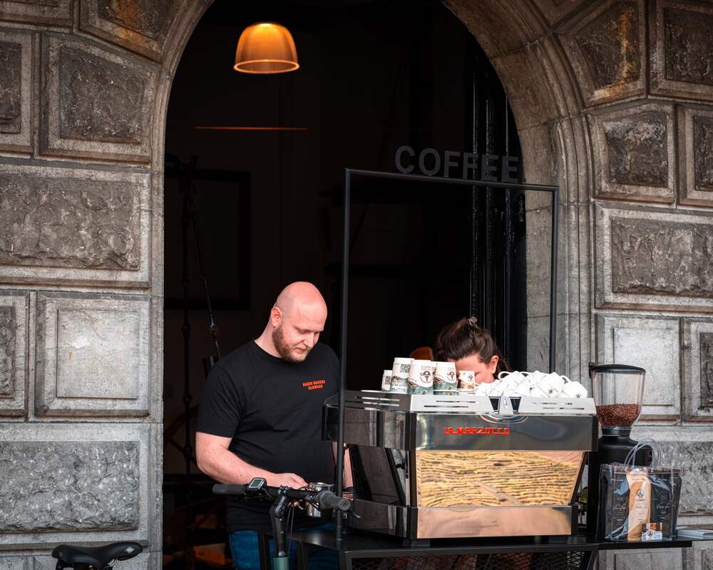 Barista achter de BakkieBar onder monumentale poort